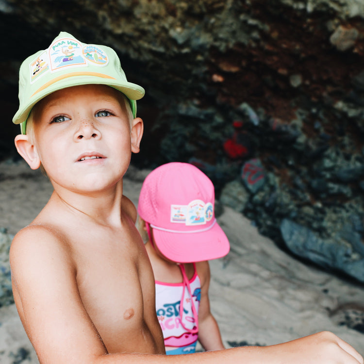 Child holding a pink cap with a natural rock formation in the background